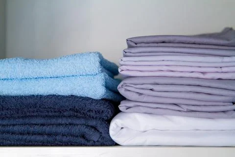Stack of fresh clean cotton bath towels and bedding on light background, closeup Stock Photos