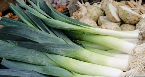 Stack of fresh leeks on a flea market counter. Fresh vegetables background. 스톡 사진