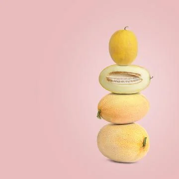 Stack of fresh melons on pale pink background. Space for text Stock Photos