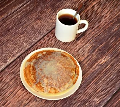 A stack of fresh pancakes with condensed milk in a plate and a cup of black.. Stock-Fotos