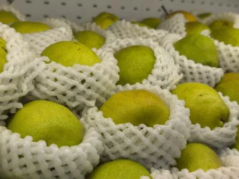 Stack of Fresh Pears with Protective Foam Netting in a Market Display Stock Photos