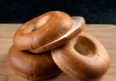 Stack of fresh plain bagels on a wooden cutting board 写真素材
