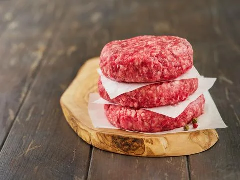 Stack of fresh raw burger patty or ground beef meat burger steak cutlets on d Foto stock