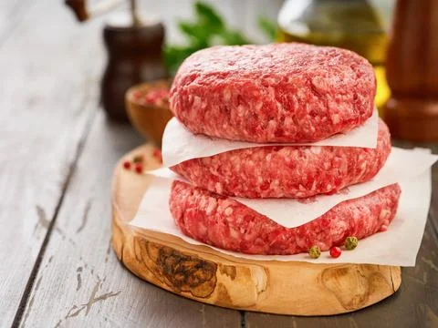 Stack of fresh raw burger patty or ground beef meat burger steak cutlets on d Foto stock
