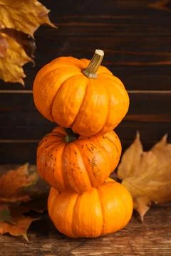 Stack of fresh ripe pumpkins and dry leaves on wooden table Foto stock