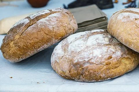 Stack of fresh rustic bread with round sprinkled flour lies on a white tablec Stock-Fotos