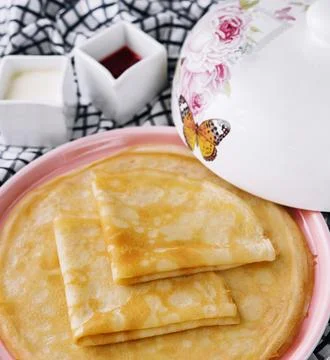 Stack of fresh thin pancakes on pink plate 스톡 사진
