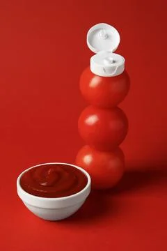Stack of fresh tomatoes with plastic cap as bottle and ketchup in bowl on r.. 스톡 사진
