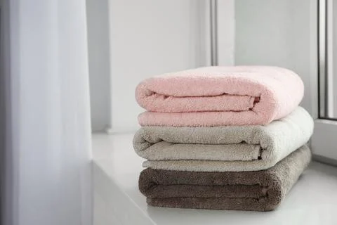Stack of fresh towels on windowsill. Space for text Fotos Stock