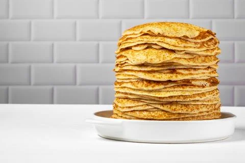 Stack of freshly baked pancakes lie in white ceramic form. Stock Photos