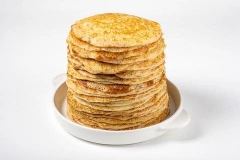 Stack of freshly baked pancakes lie in white ceramic form. Stock Photos