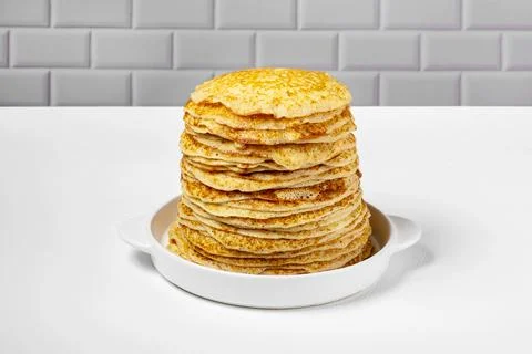Stack of freshly baked pancakes lie in white ceramic form. Stock Photos
