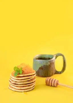 Stack of freshly home made pancakes with cup of tea isolated over bright yellow Stock Photos
