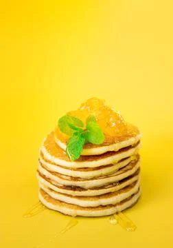 Stack of freshly home made pancakes isolated over bright yellow background Stock Photos