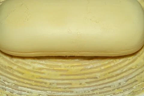 A stack of freshly made butter blocks in a wooden container for culinary use Фото