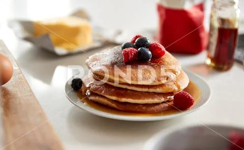 Stack Of Freshly Made Pancakes Or Crepes With Maple Syrup And Berries On Table Stock Photos