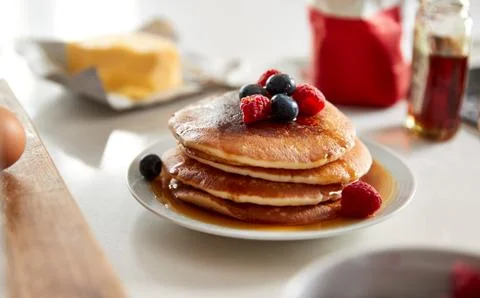 Stack Of Freshly Made Pancakes Or Crepes With Maple Syrup And Berries On Table 스톡 사진