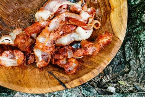 Stack of fried bacon strips in wooden bowl. Stock Photos