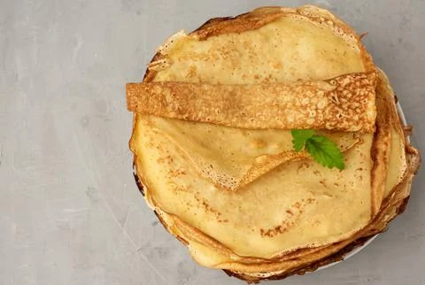 Stack of fried round pancakes on a plate, gray background, top view Stock-Fotos