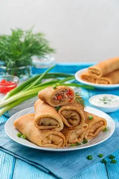 A stack of fried stuffed pancakes decorated with dill and onion on a blue bac Stock Photos