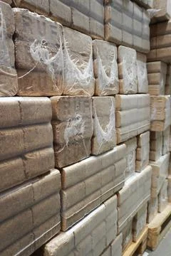 A stack of fuel briquettes made of pressed sawdust on a pallet. Stock Photos