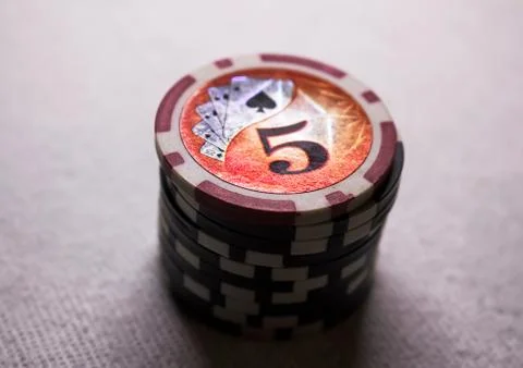 A stack of game chips with a denomination of five, against a dark background Stock Photos