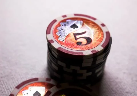 A stack of game chips with a denomination of five, against a dark background Stock Photos