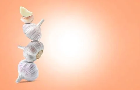 Stack of garlic bulbs and cloves on coral background, space for text Foto stock