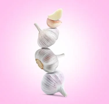 Stack of garlic bulbs and cloves on pink background Foto stock