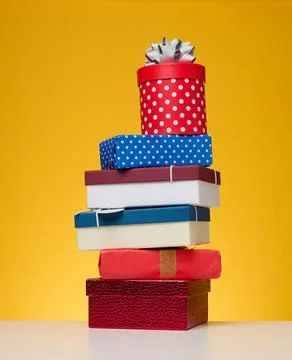 A stack of gift boxes wrapped in colorful paper on a yellow background. Hap.. 写真素材