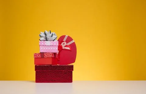 A stack of gift boxes wrapped in colorful paper on a yellow background. Hap.. Stock Photos