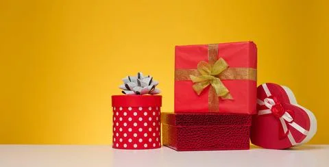 A stack of gift boxes wrapped in colorful paper on a yellow background. Ha... Stock Photos