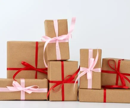 Stack of gifts in boxes wrapped in brown kraft paper and tied with silk ribbo 스톡 사진