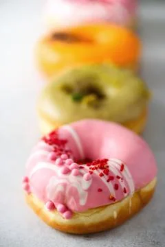 Stack of glazed colorful assorted donuts with sprinkles on grey cement Stock Photos