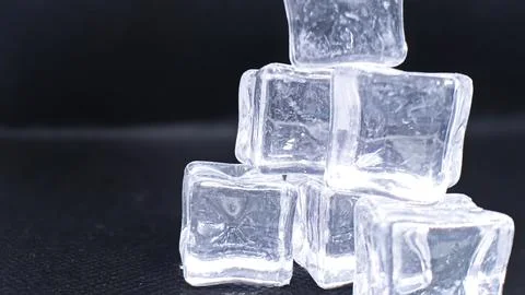 A stack of glistening ice cubes on a black background, ideal for beverage o.. Stock Photos