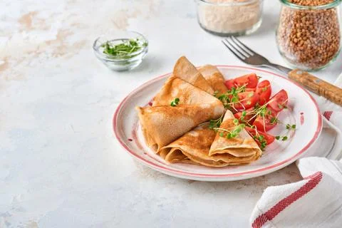 Stack of gluten free buckwheat flour crepes pancakes with cherry tomatoes and Foto stock