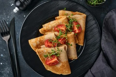 Stack of gluten free buckwheat flour crepes pancakes with cherry tomatoes and Foto stock