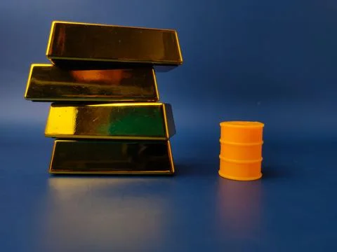Stack of gold bar with yellow oil barrel on a blue background Stock Photos