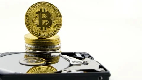 Stack of gold bitcoin tokens in front of an hdd.Worldwide virtual internet cr Stock Footage 131320296