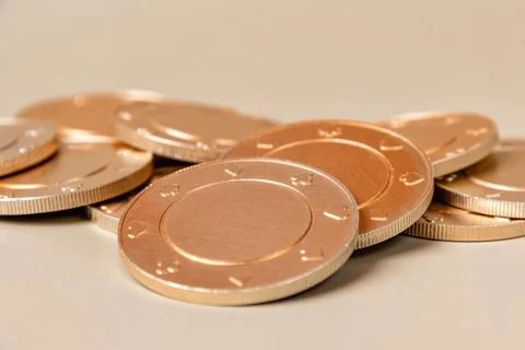 Stack of gold casino chips with a subtle texture on a light brown surface Stock Photos