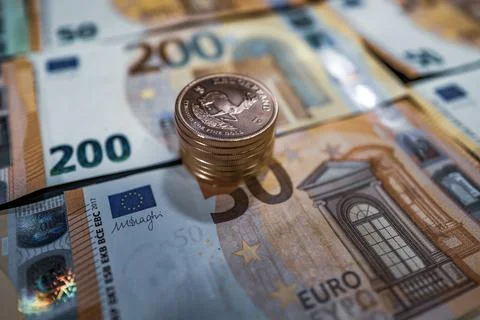 Stack of gold coins lie on spread out euro banknotes Stock Photos