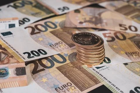Stack of gold coins lie on spread out euro banknotes Stock Photos