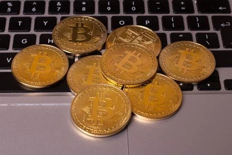 A stack of golden bitcoin coin on a silver keyboard of laptop. Virtual crypto Stock Photos