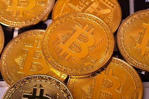 A stack of golden bitcoin coin on a silver keyboard of laptop. Virtual crypto Stock Photos