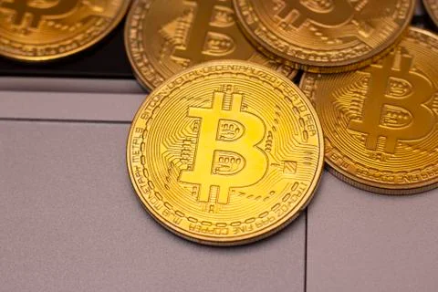A stack of golden bitcoin coin on a silver keyboard of laptop. Virtual crypto Stock Photos