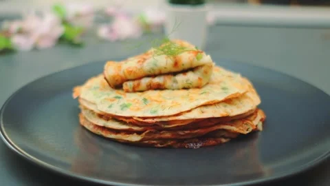 Stack of golden-brown pancakes with greens garnished with dill on plate indoors 库存影片 342882068