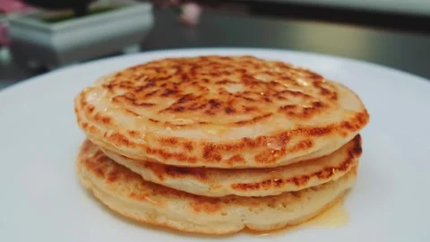 Stack of golden-brown pancakes with maple syrup on kitchen table Stock Footage 342875693