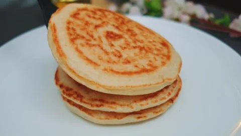 Stack of golden-brown pancakes served on white plate indoors Stock Footage 342875545