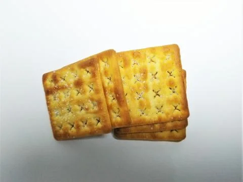 A stack of golden brown square crackers on a white background. Stock Photos