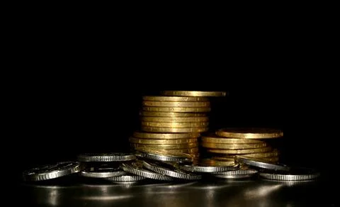 Stack of golden coins and heap of silver coins on a black background Stock-Fotos